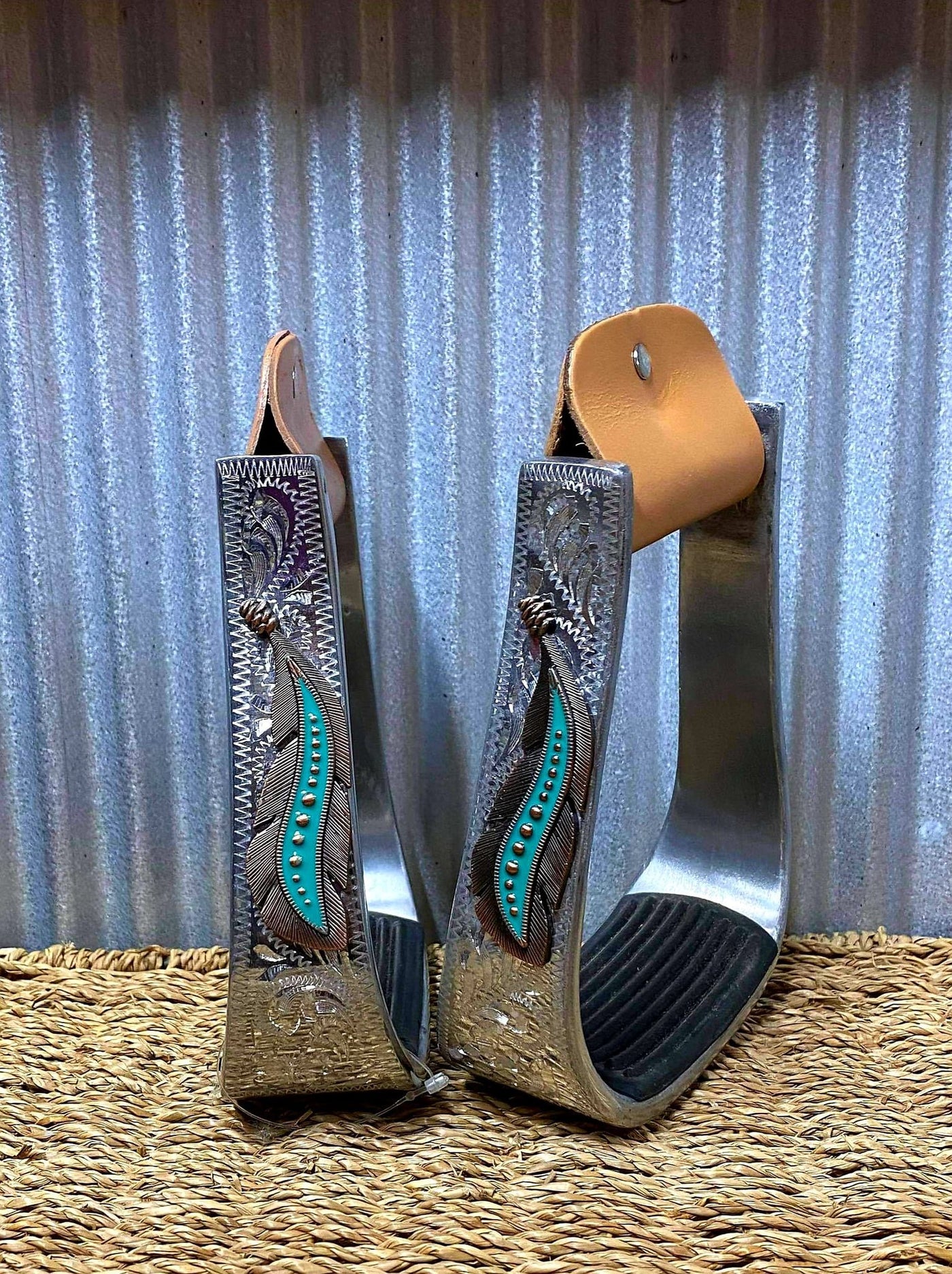 Stirrups - ®   Silver Engraved Stirrups with copper and teal feather concho on top of the engraved side.