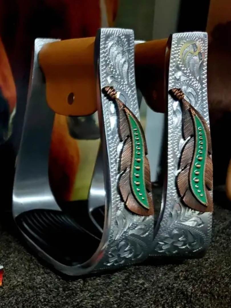 Stirrups - ®   Silver Engraved Stirrups with copper and teal feather concho on top of the engraved side.